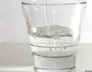 Clear glass being filled with pouring water. 